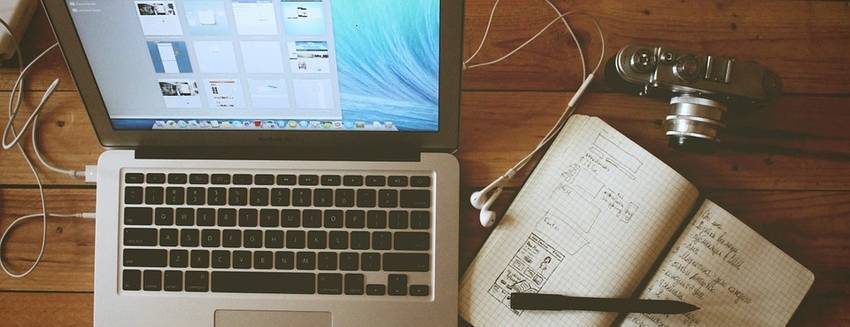 Een laptop met daarnaast een notebook